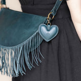 A heart-shaped teal leather bag charm with a brass lobster clasp