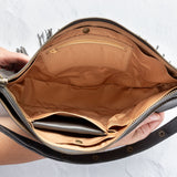 Charcoal leather fringe bag with interior pockets, held by a person against a white background