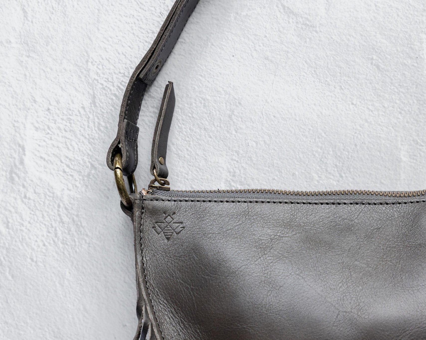 Close-up of the zipper and fringe on a charcoal leather bag