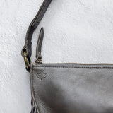 Close-up of the zipper and fringe on a charcoal leather bag