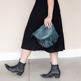 Small teal leather fringe bag held as a clutch