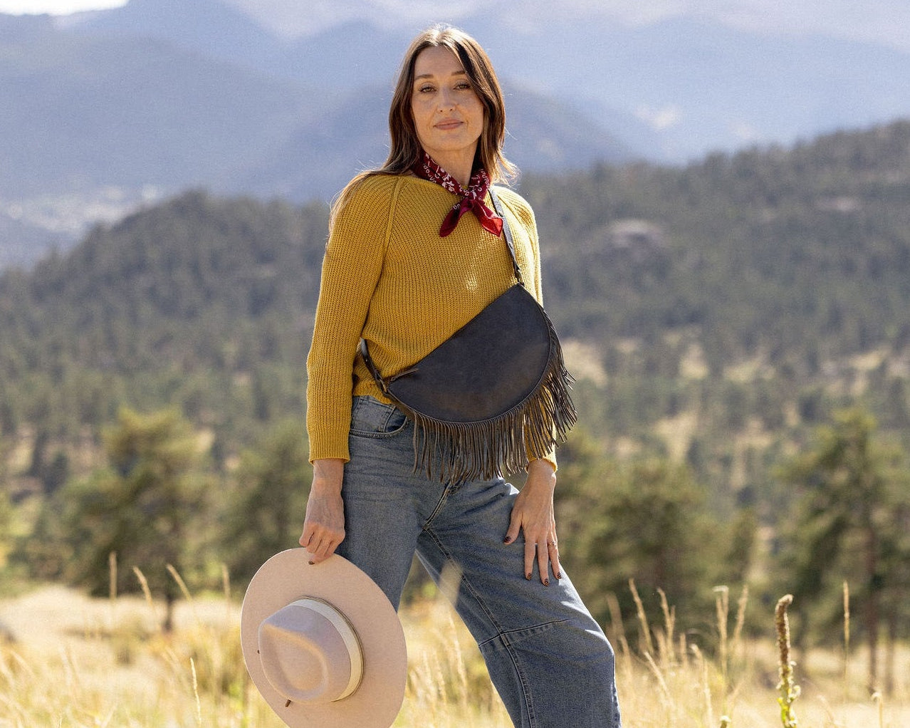 Woman wearing a large charcoal leather fringe bag outdoors