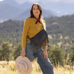 Woman wearing a large charcoal leather fringe bag outdoors