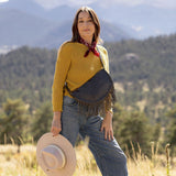 Woman wearing a large charcoal leather fringe bag outdoors