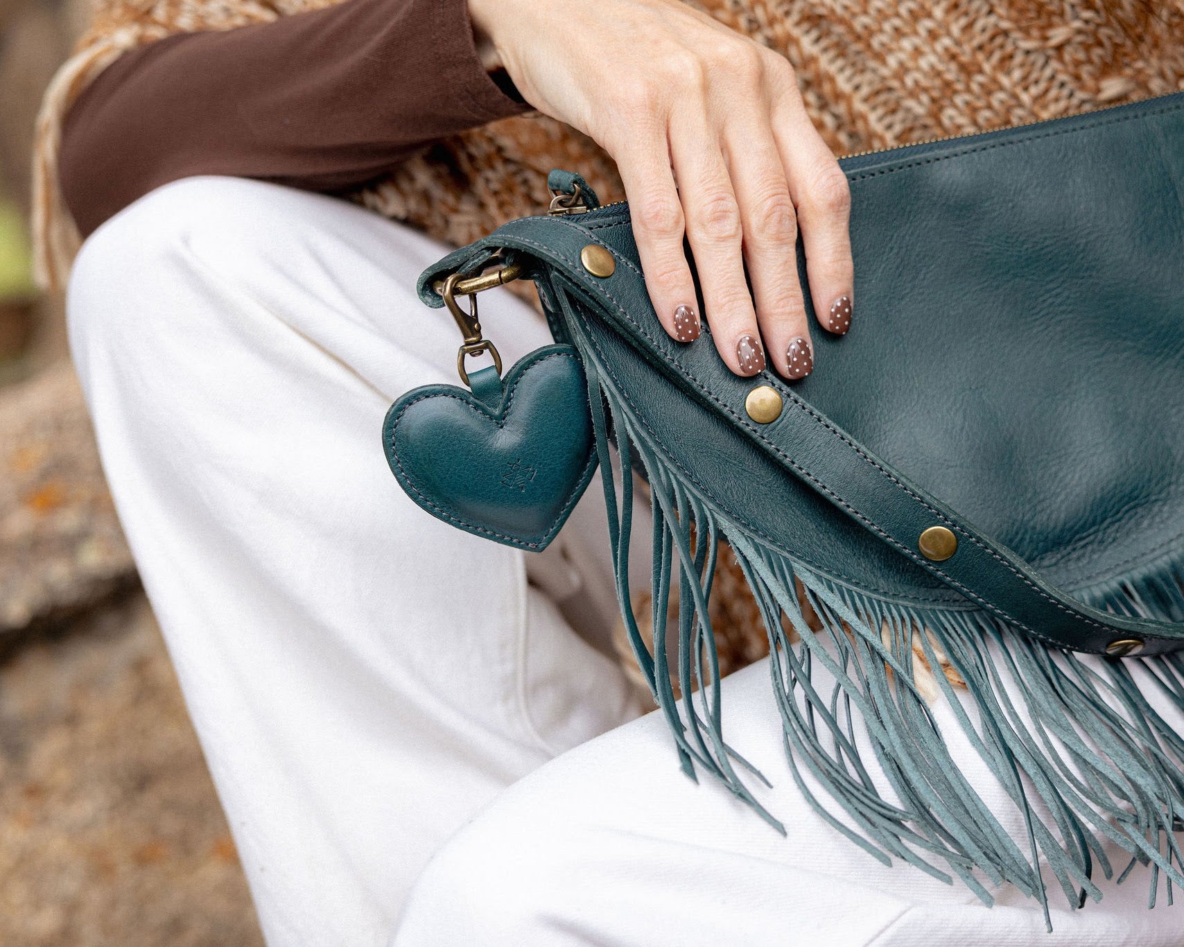 A heart-shaped teal leather bag charm with a brass lobster clasp
