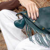 A heart-shaped teal leather bag charm with a brass lobster clasp
