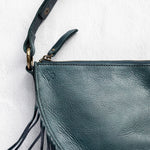 Close-up of the zipper and fringe on a teal leather bag