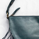 Close-up of the zipper and fringe on a teal leather bag