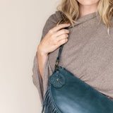 A teal leather flower-shaped bag charm with a metal lobster clasp