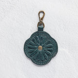 A teal leather flower-shaped bag charm with a metal lobster clasp