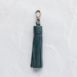 Teal leather tassel keychain on a white textured background