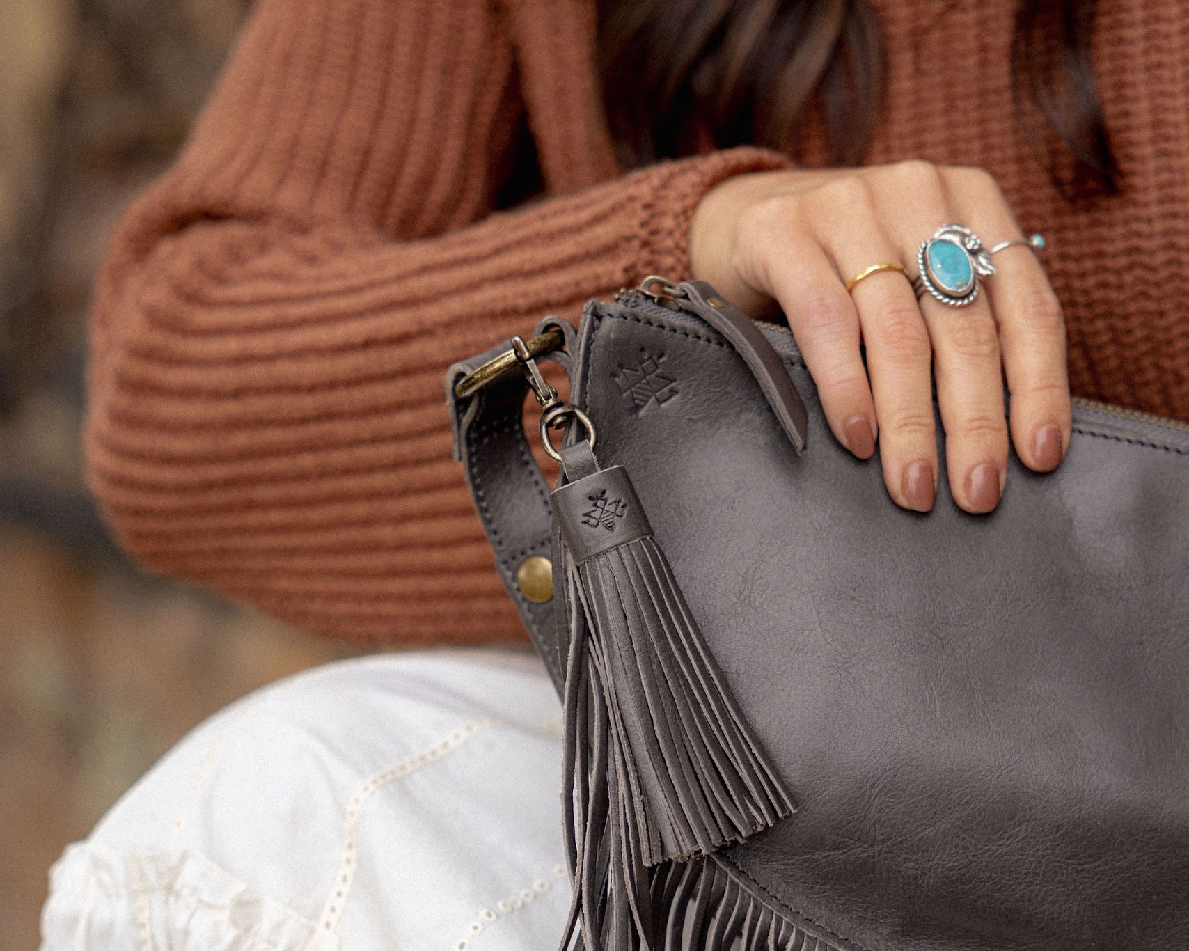 Charcoal leather tassel keychain on a white textured background