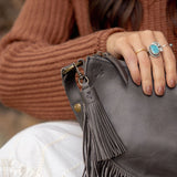 Charcoal leather tassel keychain on a white textured background