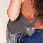 A heart-shaped charcoal leather bag charm with a brass lobster clasp