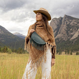 Woman wearing a medium teal leather fringe bag outdoors