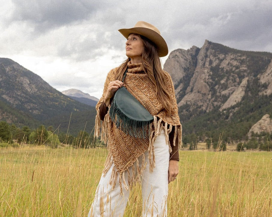 Woman wearing a medium teal leather fringe bag outdoors