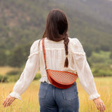 Woman wearing the Woven Terracotta & Seashell Biggie Bee crossbody in a mountain field