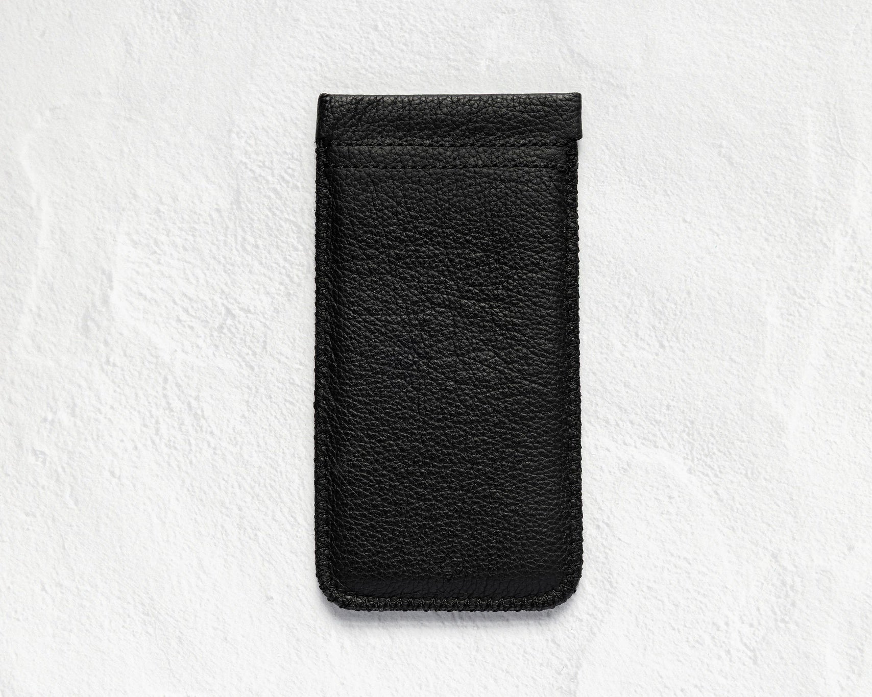 A black textured leather phone pouch or sleeve, shown vertically against a light gray, textured background.
