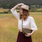 Woman wearing the Woven Sage & Espresso Queen Bee crossbody