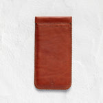A brown leather phone pouch with visible stitching, shown flat against a textured white background.