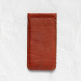 A brown leather phone pouch with visible stitching, shown flat against a textured white background.