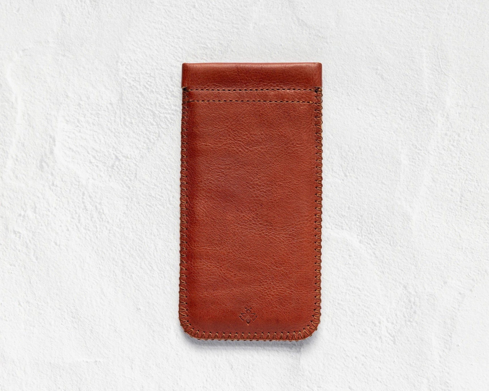 A brown leather phone pouch with visible stitching, shown flat against a textured white background.