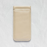 A minimalist beige leather phone pouch or card holder with a single horizontal card slot, shown flat against a textured white background.
