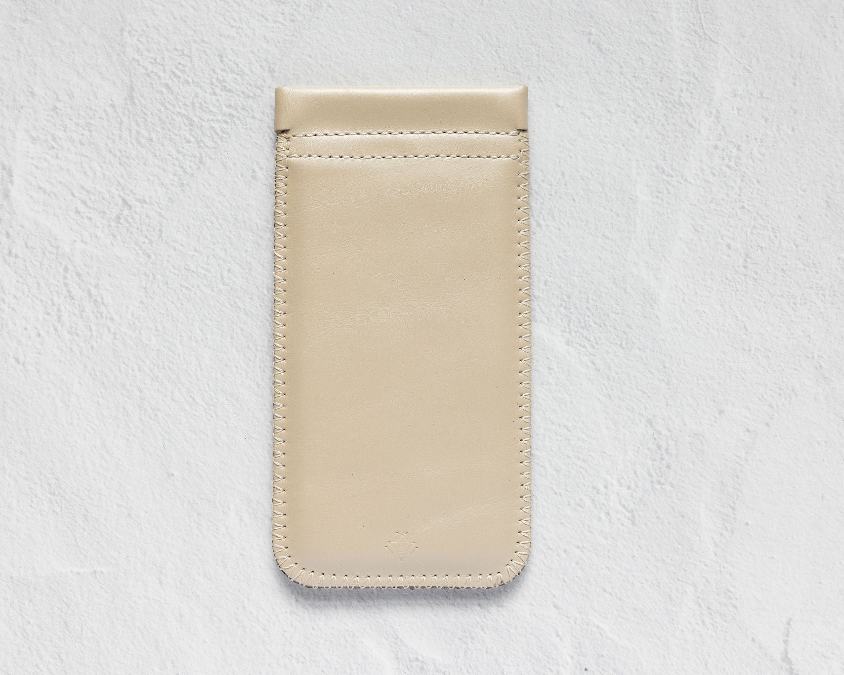 A minimalist beige leather phone pouch or card holder with a single horizontal card slot, shown flat against a textured white background.