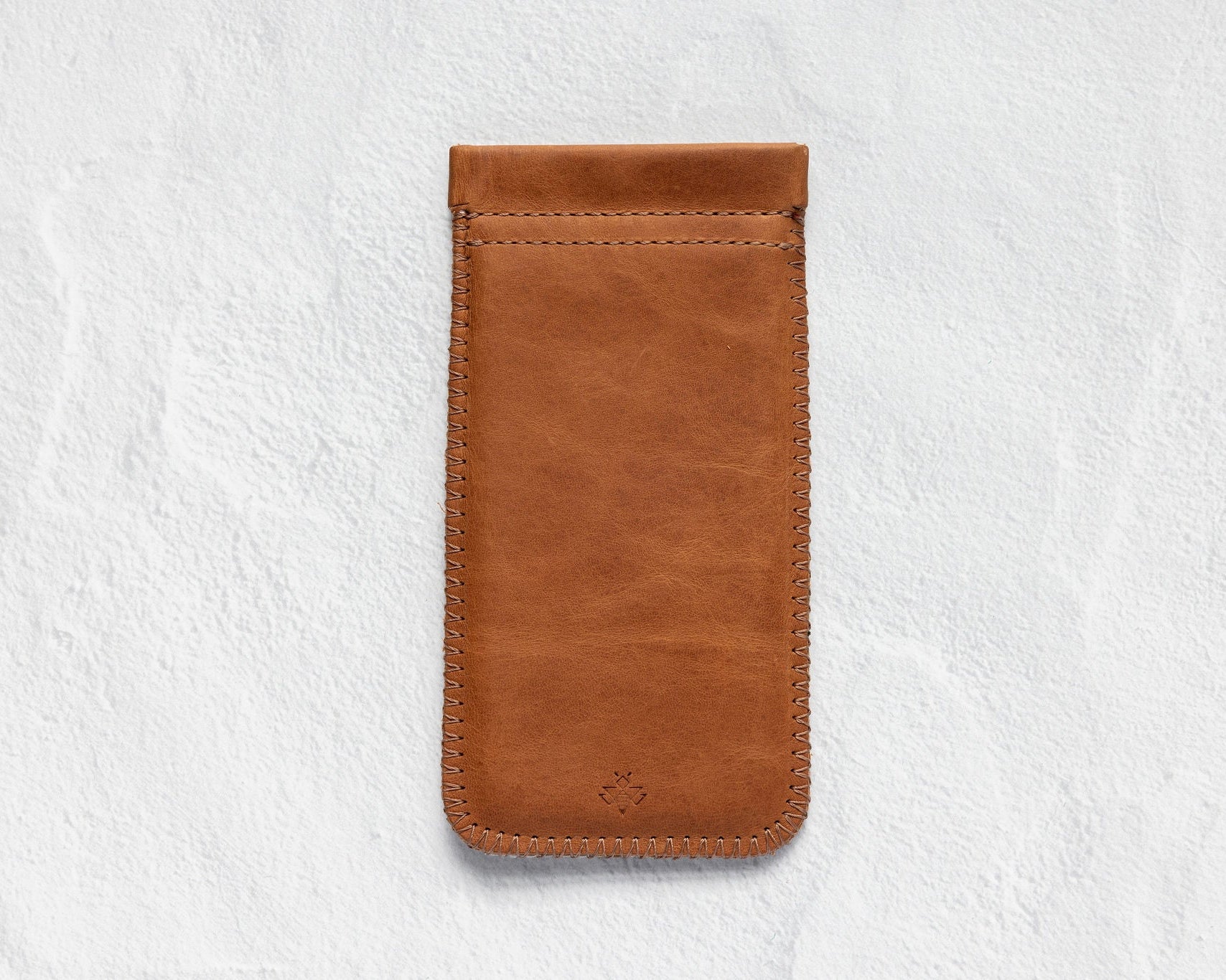 A brown leather phone pouch with a stitched border and a small debossed logo near the bottom, displayed on a textured white background.