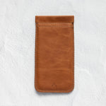 A brown leather phone pouch with a stitched border and a small debossed logo near the bottom, displayed on a textured white background.