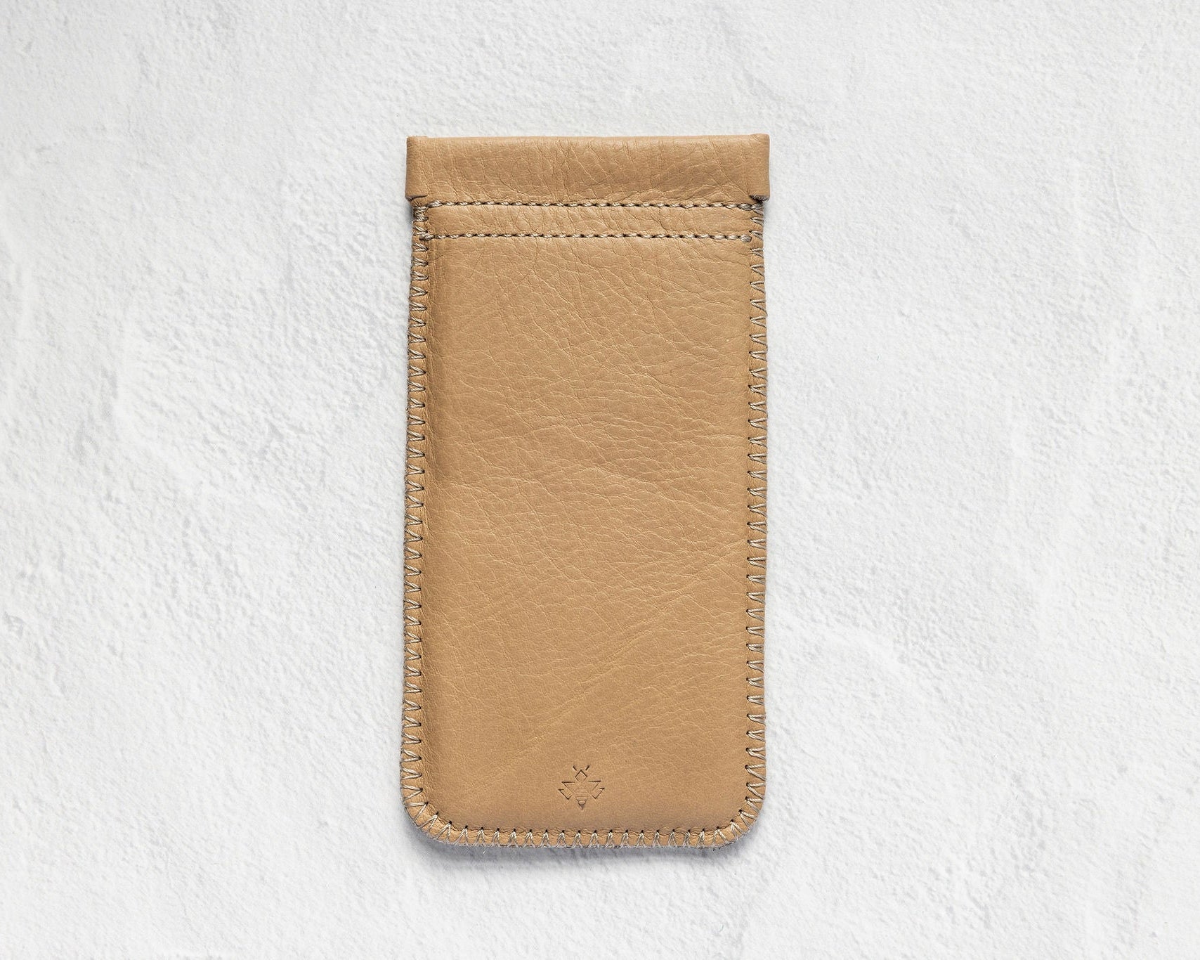 A tan leather phone pouch with a stitched top loop, displayed flat against a textured white background.