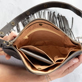 Charcoal leather fringe bag with interior pockets, held by a person against a white background