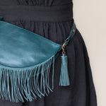 Teal leather tassel keychain on a white textured background