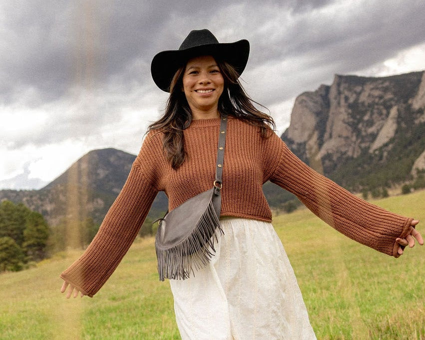 Woman wearing a medium charcoal leather fringe bag outdoors