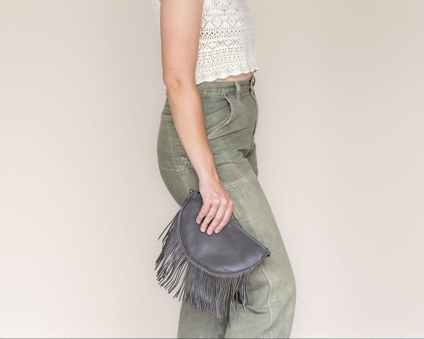 Small charcoal leather fringe bag held as a clutch