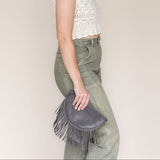 Small charcoal leather fringe bag held as a clutch