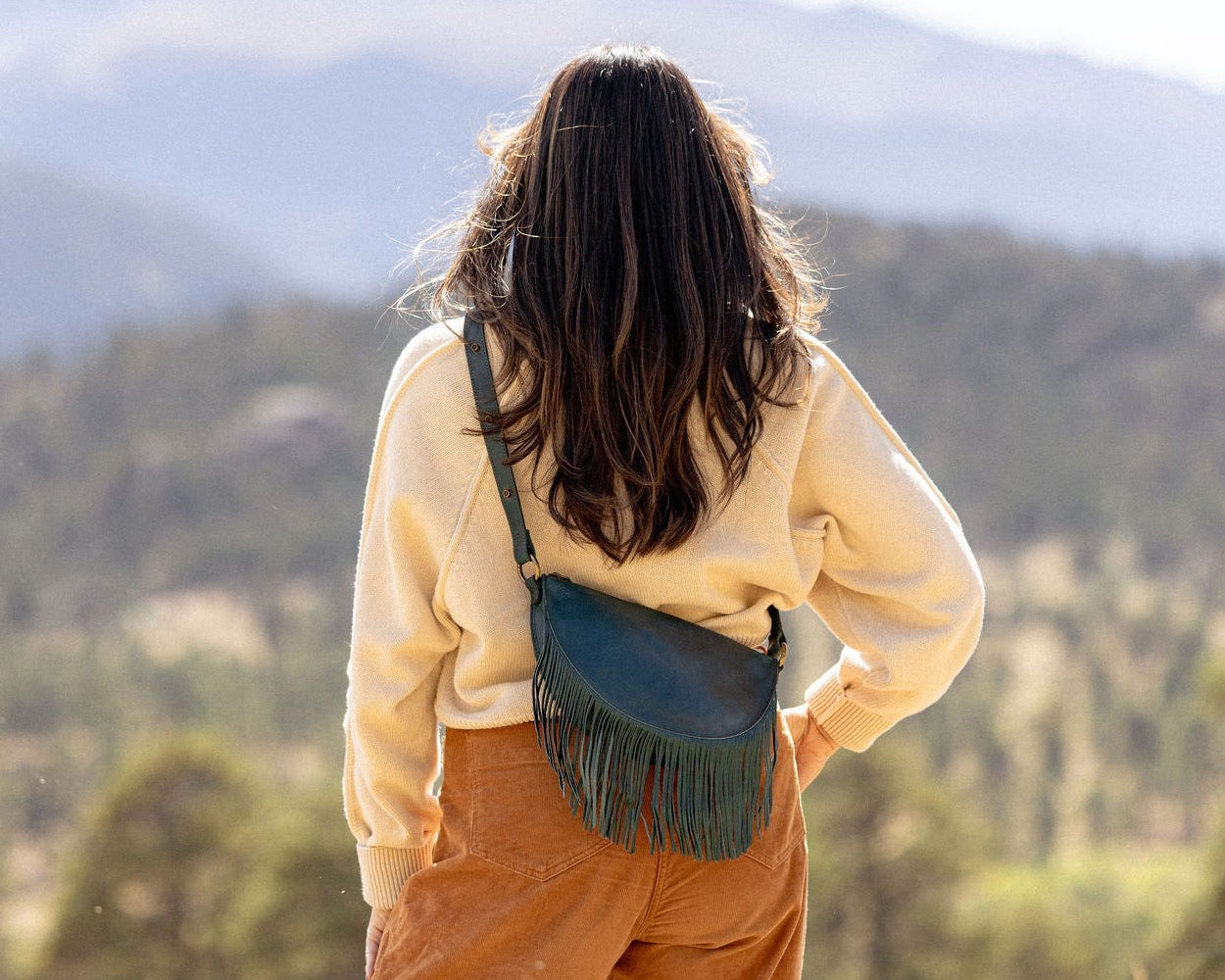 Woman wearing a small teal leather fringe bag outdoors