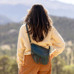 Woman wearing a small teal leather fringe bag outdoors