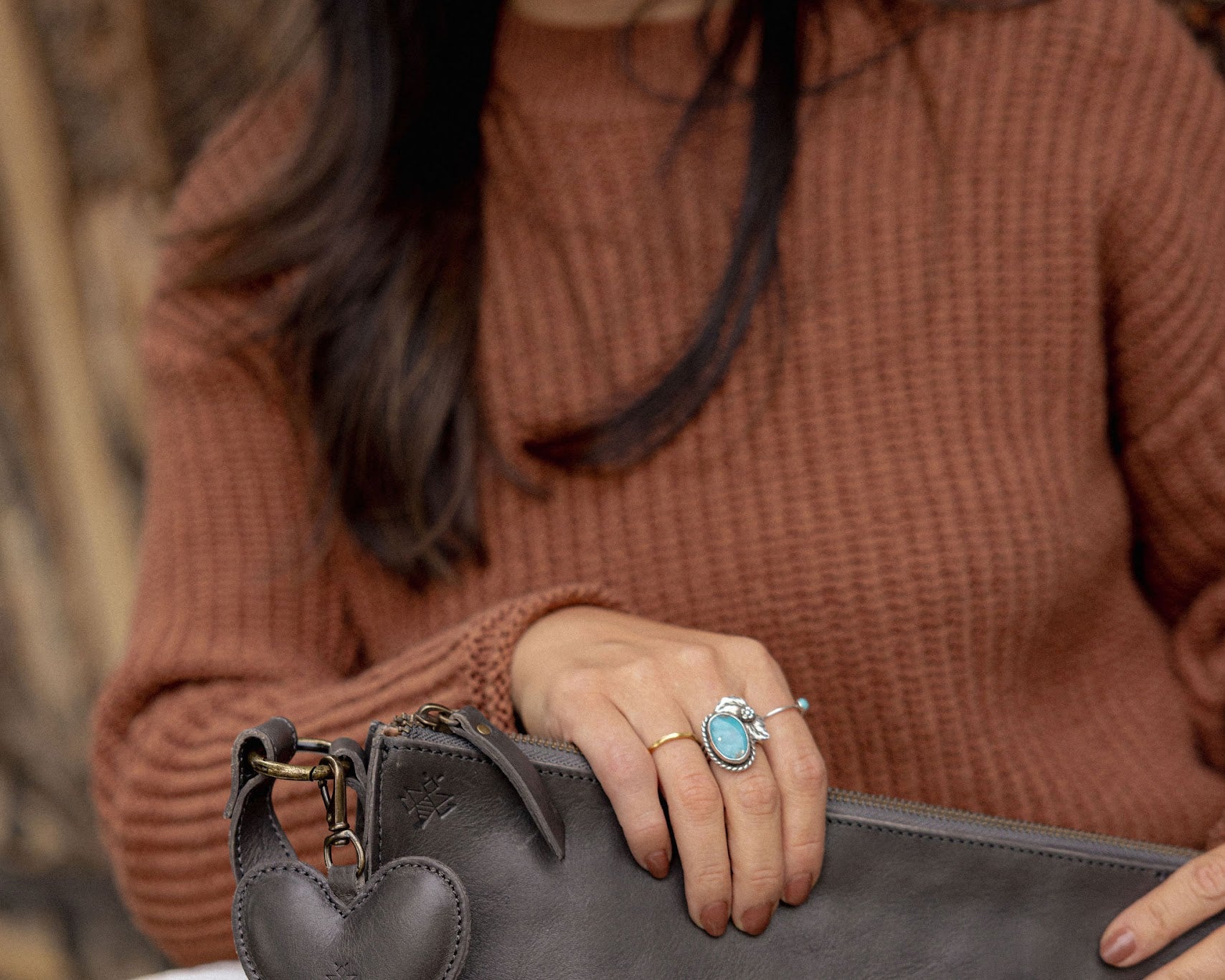 A heart-shaped charcoal leather bag charm with a brass lobster clasp
