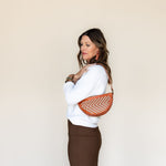 The Woven Terracotta & Seashell Bee worn as a shoulder bag
