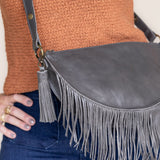 Charcoal leather tassel keychain on a white textured background