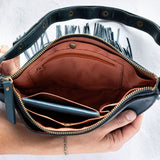 Teal leather fringe bag with interior pockets, held by a person against a white background