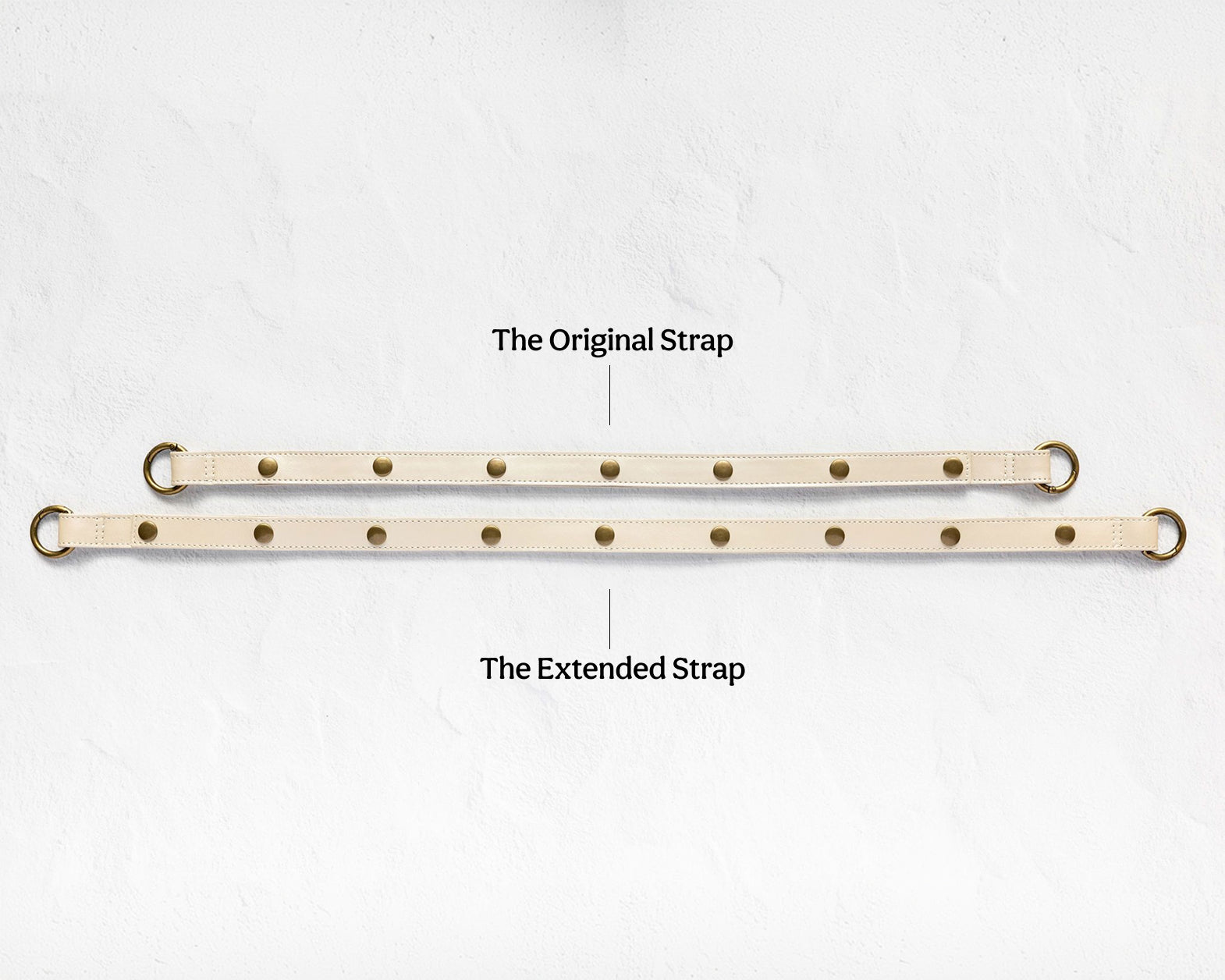 Two beige adjustable leather straps with brass grommets are displayed on a light textured background, labeled 'The Original Strap' and 'The Extended Strap'.