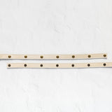 A beige leather belt with brass hardware, displayed in two parallel horizontal positions on a textured white background.
