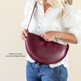 Person holding a burgundy handbag against a beige background