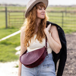 Woman wearing a hat and carrying a bag in an outdoor setting