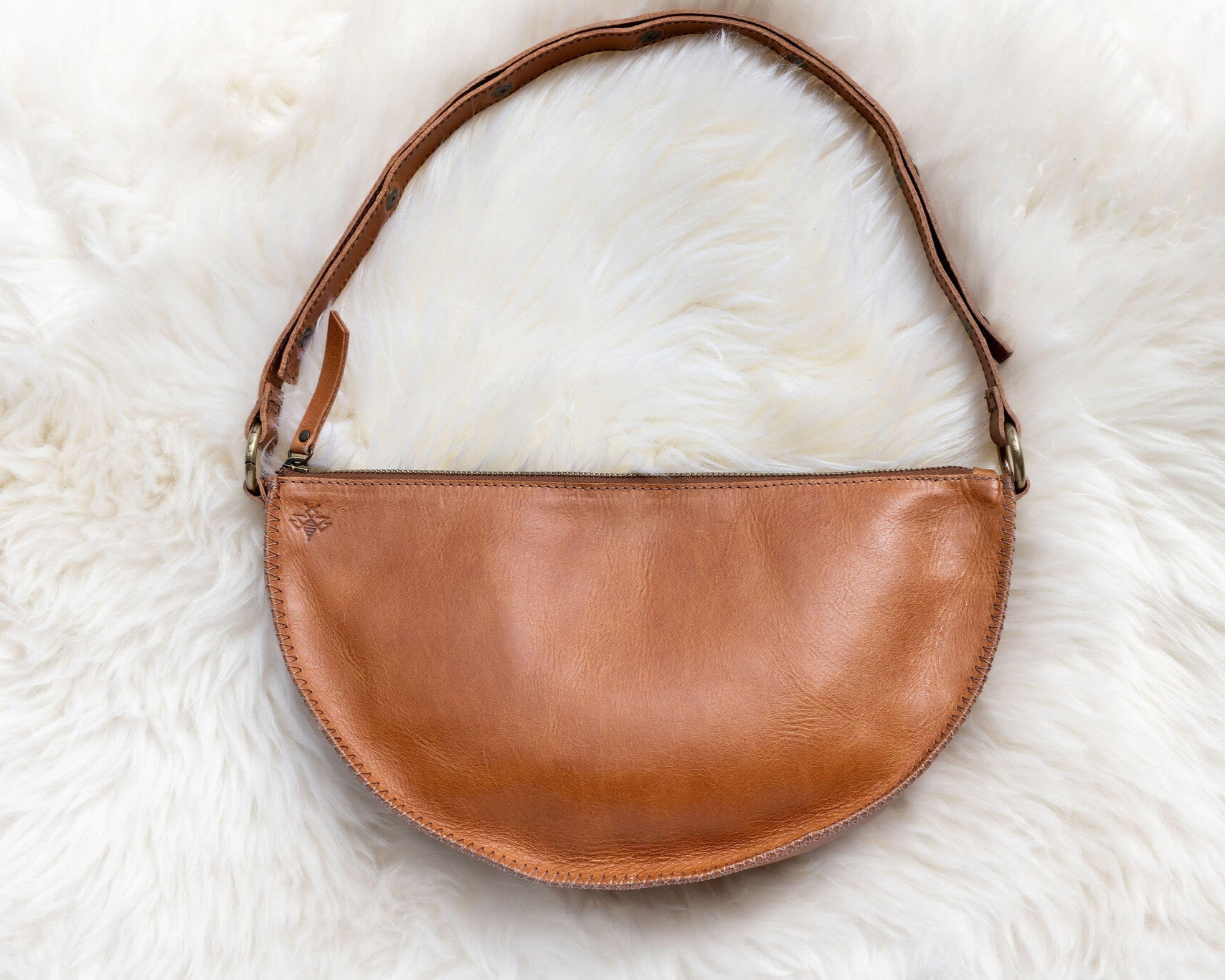 Brown leather handbag on a white fur surface