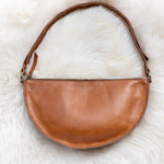 Brown leather handbag on a white fur surface