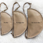 Three beige pouches labeled 'The Bee', 'The Biggie Bee', and 'The Queen Bee' on a white fur background.