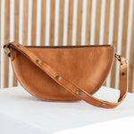Brown leather bag on a white surface with a wooden background